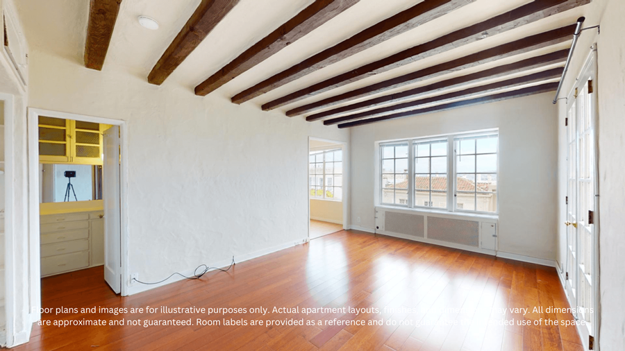 A spacious room with wooden floors and a high ceiling with exposed beams.